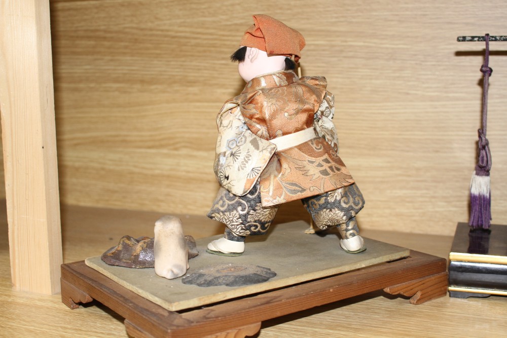 A Japanese late Meiji period composition and fabric figure of a boy farmer holding an adze with puppy seated nearby, mounted on display